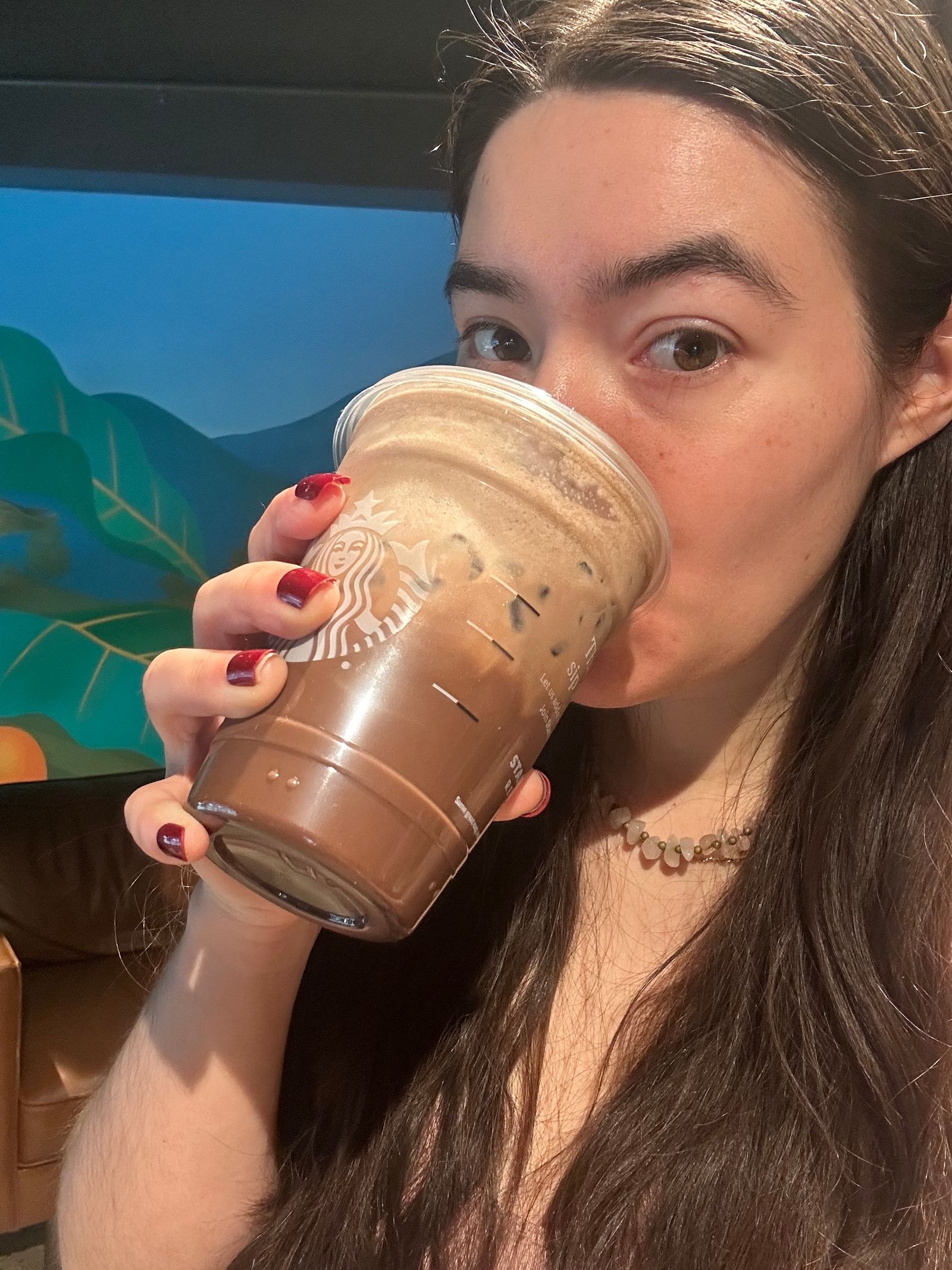 Closeup of Caroline Tien drinking the Starbucks iced mocha with chocolate protein cold foam
